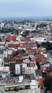 Kırmızı çatıları ve yüksek binaları olan büyük, yoğun bir Avrupa şehri. Manzara, manzara. Ufukta dağlar ve ormanlar görülebilir. Büyük bir şehirde hayat.