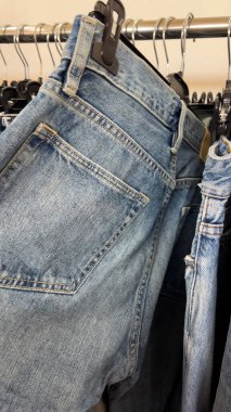 Bir kadın bir mağazada askılarda asılı olan kotların üzerinden koşar. Alışveriş süreci, kot seçimi ve kostüm seçimi konsepti.