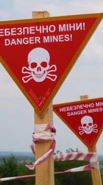 Tehlike, mayın ve eskrim bantları yazılı işaretler yerleşim yerinin önünde. Ukrayna köylerindeki mayınlı bölgeler. Rus-Ukrayna Savaşı 2022-2023. İnsani mayın temizleme kavramı