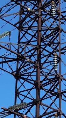 Mavi gökyüzüne kablolarla bağlı yüksek voltajlı bir elektrik direği. Elektrik üretimi ve taşımacılığı. Enerji güvenliği