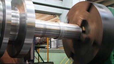 Büyük bir metal parçası, bir fabrika atölyesindeki metal işleme makinesinde dönüyor. Türbin bileşenleri ve ağır parçaların endüstriyel imalatı.