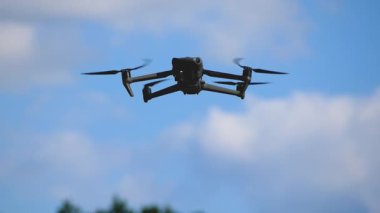 Bir dron açık mavi gökyüzünde süzülür. Yükseklikten hava fotoğrafçılığı, video ve izleme için ideal.