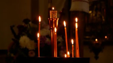 Mihrabın yanındaki karanlık Ortodoks kilisesinde mumlar yanar. Namaz, hatıra ve sessizlik atmosferi.