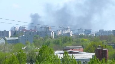 Şehirdeki büyük bir yangın sırasında yüksek binaların üzerinde kara duman yükseliyor. Şehir faciası, acil durum.