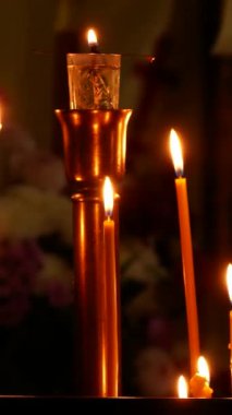 Mihrabın yanındaki karanlık Ortodoks kilisesinde mumlar yanar. Namaz, hatıra ve sessizlik atmosferi.