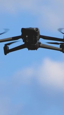 Bir dron açık mavi gökyüzünde süzülür. Yükseklikten hava fotoğrafçılığı, video ve izleme için ideal.