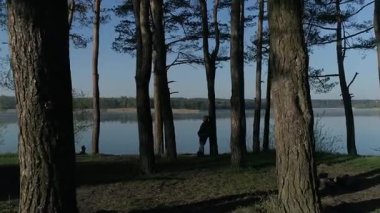 Tanınmayan yaşlı bir adam çam ağaçlarının arasında gölün kıyısındaki bir uçurumun kenarında duruyor. Adam bir çam ağacına yaslandı ve düşündü, hayal etti. Altın Çağ. Rahatlama, meditasyon kavramı.