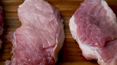 Mutfaktaki ahşap bir tahtanın üzerinde büyük taze domuz eti parçaları. Diyetteki domuz eti. Akşam yemeği için taze et..