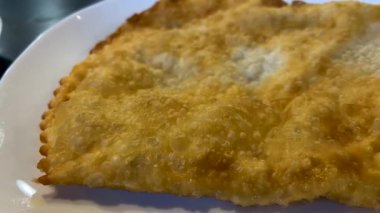 Büyük, lezzetli, etli ve peynirli bir hamur köftesi bir kahve dükkanında bir tabakta yatıyor. Lezzetli ve besleyici hamur dolması..