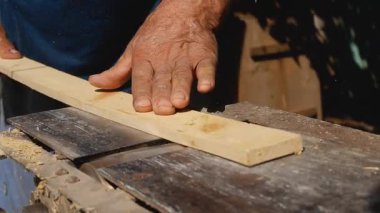 Bir adamın eli ahşap bir kalası yüzeyi öğüten ve pürüzsüz hale getiren bir ahşap işçiliği makinesinden geçirir. Ev ahşap atölyesi, ahşap işleme..