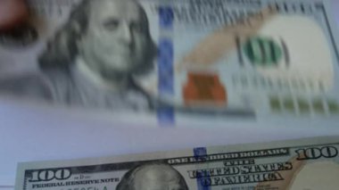 Kadınların elleri masaya yüz dolarlık banknotları yerleştirir ve onları üst üste dizer. Finans kavramı, para tasarrufu, aile bütçesi, yatırımlar, finansal okur yazarlık.