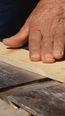 Bir adamın eli ahşap bir kalası yüzeyi öğüten ve pürüzsüz hale getiren bir ahşap işçiliği makinesinden geçirir. Ev ahşap atölyesi, ahşap işleme..