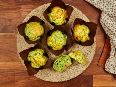 Homemamde savory muffins with spinach, red bell paper and feta, in brown paper muffin liners, on a ceramic plate