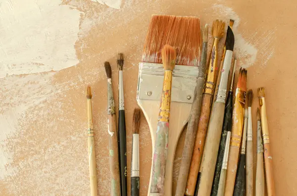 stock image A collection of old painting brushes in working condition placed on a surface with white brushstrokes