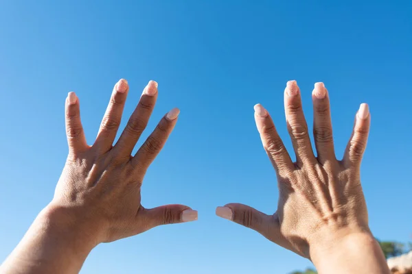 womans hands showing all ten fingers on a blue sky background,
