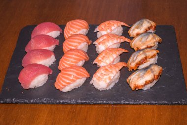 Siyah tabakta çeşitli suşiler servis ediliyor. Japon yemeği.,