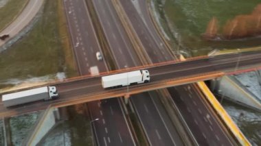Karavanı olan beyaz bir kamyon, yoğun araba ve kamyon trafiğiyle köprüden geçiyor. Malların uluslararası kargo lojistik rotası boyunca nakliyesi ve teslimi.