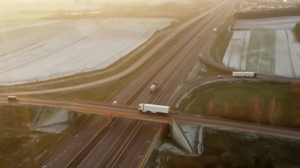 トレーラー付きの白いトラックは 車やトラックの重い交通で高速道路を横断する橋の上を走行します 国際貨物輸送路における貨物の輸送及び引渡し — ストック動画