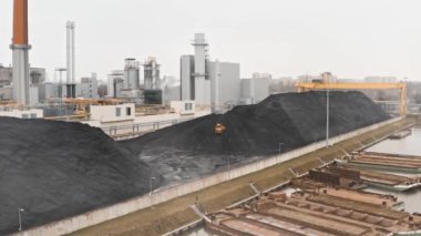 Sürüngen bir buldozer, ısıtma mevsiminde bir termik santralin fosil yakıt deposunda ısıtma konutları için kömür rezervlerini büyük bir yığına ayırıyor..