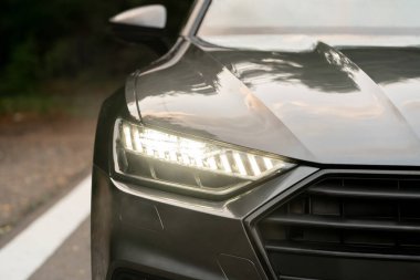 Yol kenarında duran modern bir arabanın ışıklı farları.