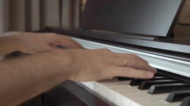 Erkek bir piyanist evde dijital bir elektronik piyanonun klavyesinde çalar. Ev piyano dersleri.