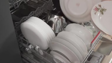 Kirli tabakları bulaşık makinesine koyan bir adam. Mutfağı temizliyorum..