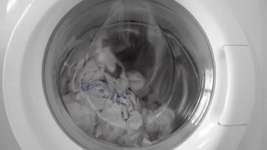 Çamaşır yıkama ya da durulama sırasında beyaz çarşaf bir çamaşır makinesinin varilinde döner.