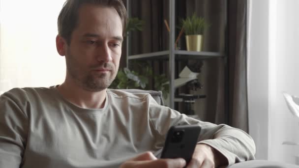 Muž Lhostejně Podívá Obrazovku Smartphonu Prolistuje Obsah Zatímco Doma Známky — Stock video