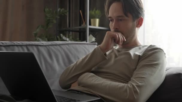 Een Man Werkt Aan Een Laptop Liggend Bank Thuis Een — Stockvideo