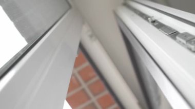 Odayı havalandırdıktan sonra, adam PVC plastik pencereyi kapatır ve kilitleme mekanizmasının kolunu öyle bir çevirir ki pencere çerçevesi mühürleyicisine hava basar ve evi sıcak tutar..
