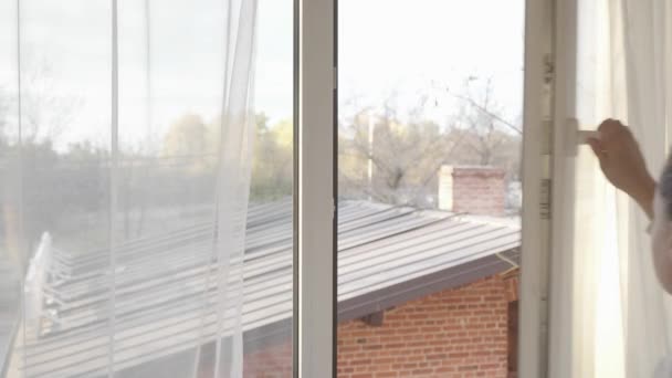女人紧紧地关上敞开着的窗户 转动着聚氯乙烯塑料窗框上的把手 拉开透明的郁金香窗帘 — 图库视频影像