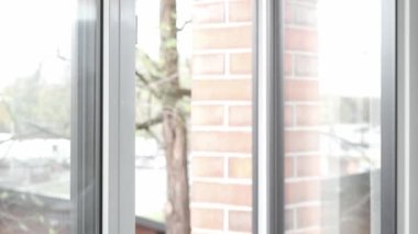 Bir adamın eli, odayı havalandırdıktan sonra, açık PVC plastik pencereyi kapatır ve pencere çerçevesini sıkıca kapatmak ve odayı sıcak tutmak için kilit mekanizmasının kolunu çevirir..