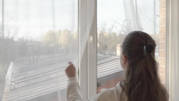 女人拉开透明的郁金香窗帘 转动聚氯乙烯塑料窗框上的把手 轻轻打开窗户 通过一个小缝隙给房间通风 — 图库视频影像