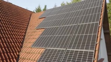 Katı silikon kristalden yapılmış modern fotovoltaik tek kristalli güneş panelleri, evin kiremitli çatısına güneş ışığını elektrik akımına dönüştürme verimliliğinin artmasıyla kurulmuştur..