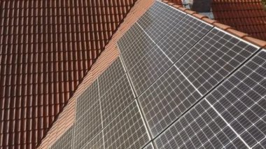 Fotovoltaik güneş panelleri özel bir evin kiremitli çatısına monte edilir. Elektrik faturalarını ödemenin maliyetini düşürmek için güneş enerjisiyle çalışan bir ev elektriği tedarik sistemi..
