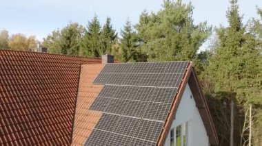Özel bir evin kiremitli çatısına yerleştirilmiş fotovoltaik güneş hücrelerinden oluşan bir ev sistemi. Özel evlerin elektriklenmesi.