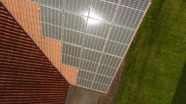 Özel bir evin kiremitli çatısına yerleştirilmiş fotovoltaik güneş panellerinde güneş parlaması. Elektrik faturalarını ödemenin maliyetini düşürmek için güneş enerjisiyle çalışan bir ev elektriği tedarik sistemi..