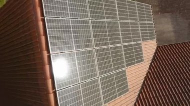 Fotovoltaik güneş modüllerine özel bir evin kiremitli çatısına yerleştirilmiş güneş patlaması. Elektrik faturalarını ödemenin maliyetini düşürmek için güneş enerjisiyle çalışan bir ev elektriği tedarik sistemi..