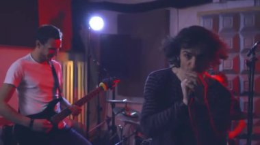 Bir rock grubunun karizmatik solisti, albümü kaydetmeden önce canlı performans sırasında kameraya bakarak duygusal olarak bir şarkıyı mikrofona kaydediyor..
