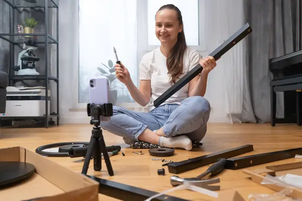 A vlogger girl records a video tutorial on assembling furniture for her channel on her phone camera. An influencer woman conducts a video broadcast about her life for subscribers of her blog.