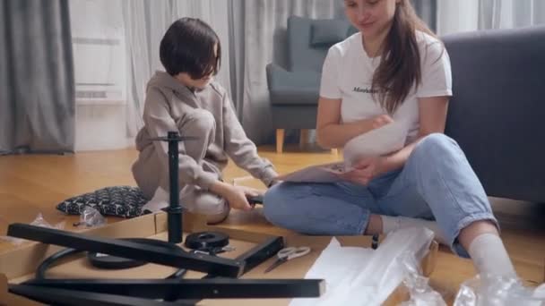 Child Sitting Next His Mother Independently Assembles New Chair Parts — Stock Video