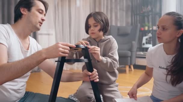 Liten Pojke Hjälper Sina Föräldrar Montera Nya Möbler Genom Att — Stockvideo
