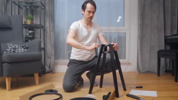 Mężczyzna Sam Naprawia Krzesło Klęcząc Przed Narzędziami Ręcznymi Częściami Mebli — Wideo stockowe
