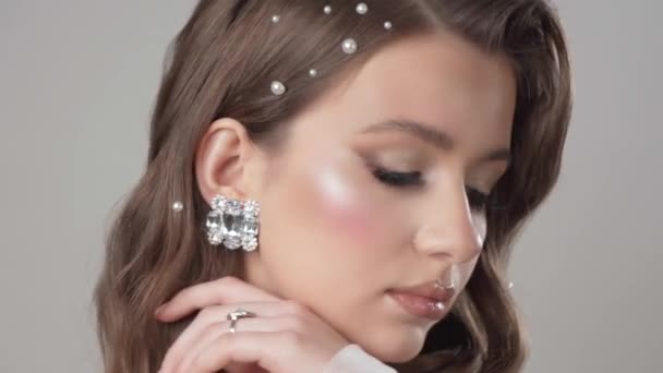 少女モデルは ダイヤモンドのイヤリング リング 真珠と貴重な石のネックレスを披露しています 白い背景にスタジオに閉じ込められたエレガントな女性の肖像画 — ストック動画