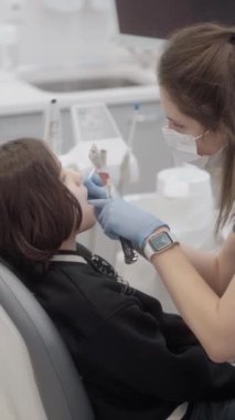 Bir pediatrik dişçi bir çocuğun bebek dişlerinin florasyonunu yapar. Flüorürün bakımı ve ağız hijyeninin korunması için kullanılması. Hasta dişçinin ofisinde..