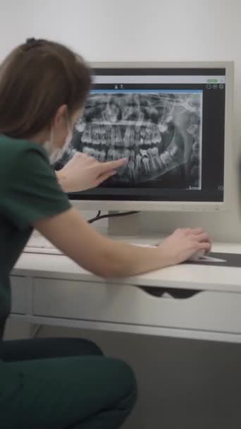 牙医在病人下巴的X光片上显示牙齿的根部 牙齿矫正师的预约及谘询 牙科诊所牙病的诊断 — 图库视频影像