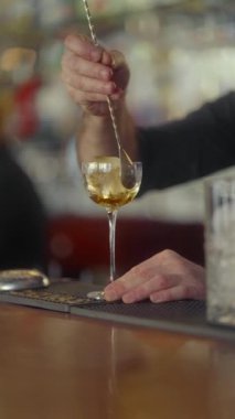 Barmen alkollü kokteyl yapmak için bardakta ezilmiş buzla viskiyi karıştırmak için bir kaşık kullanıyor. Buzlu bir bardakta soğuk viski.