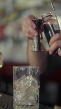 Bir barmen, bir zencefilden gelen karışımı ezilmiş buzla soğuk bir bardağa ölçer. Restoran barında ferahlatıcı bir alkollü kokteyl hazırlarken dikey bir çekim..