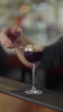 Barmen kokteyli bambu şişine bağlanmış ekmek dilimleriyle süslüyor. Bardakta alkollü kokteyl..