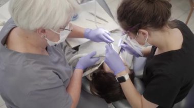 Pediatrik dişçi, asistanın desteğiyle, hastanın dişlerini tedavi eder. Bir doktor ve bir diş asistanı arasındaki takım çalışması. Diş hekimliğinde tıbbi bakım..